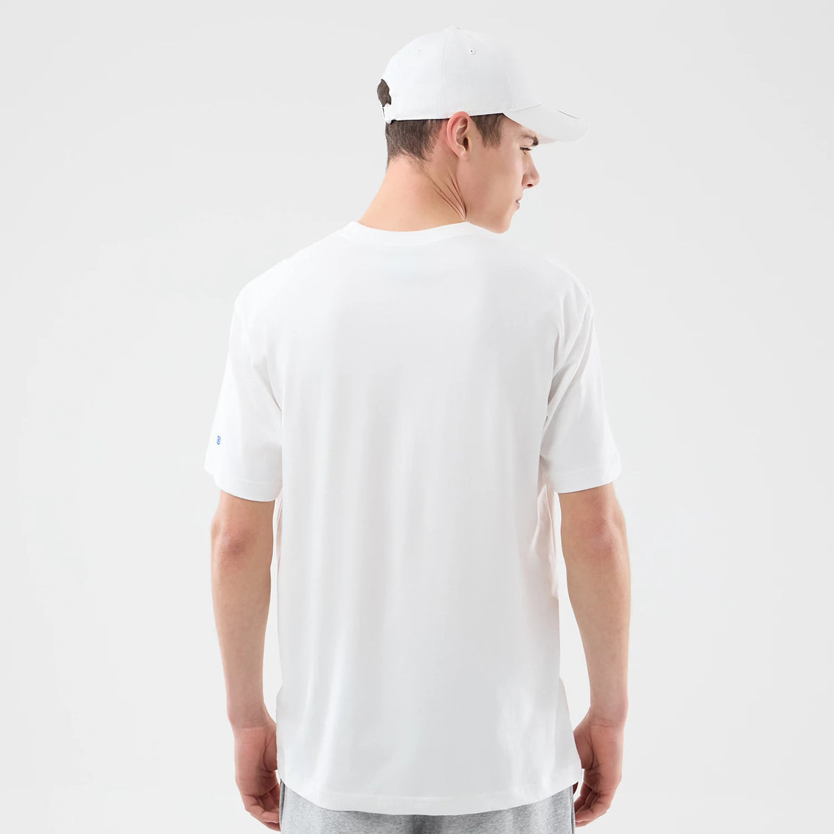 New Era New York Knicks Space Jam 2 X NBA White T-Shirt, back view on-model showcasing a plain white back with a small printed New Era logo on the left sleeve, paired with a plain white cap.