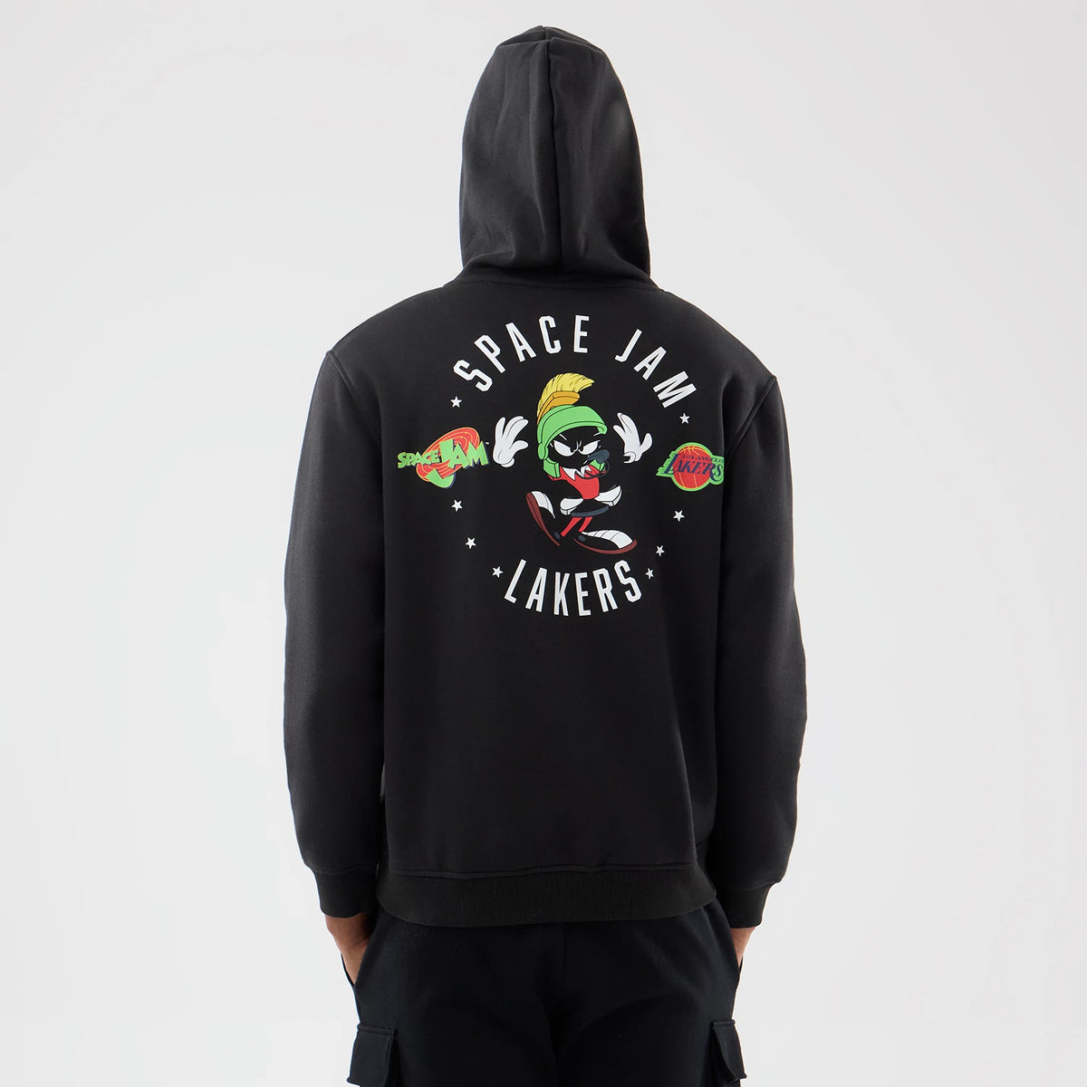 New Era LA Lakers Space Jam 2 X NBA Black Pullover Hoodie, back view showing printed Space Jam graphics with Marvin the Martian at the centre, surrounded by Space Jam and Lakers logos, worn with dark trousers.