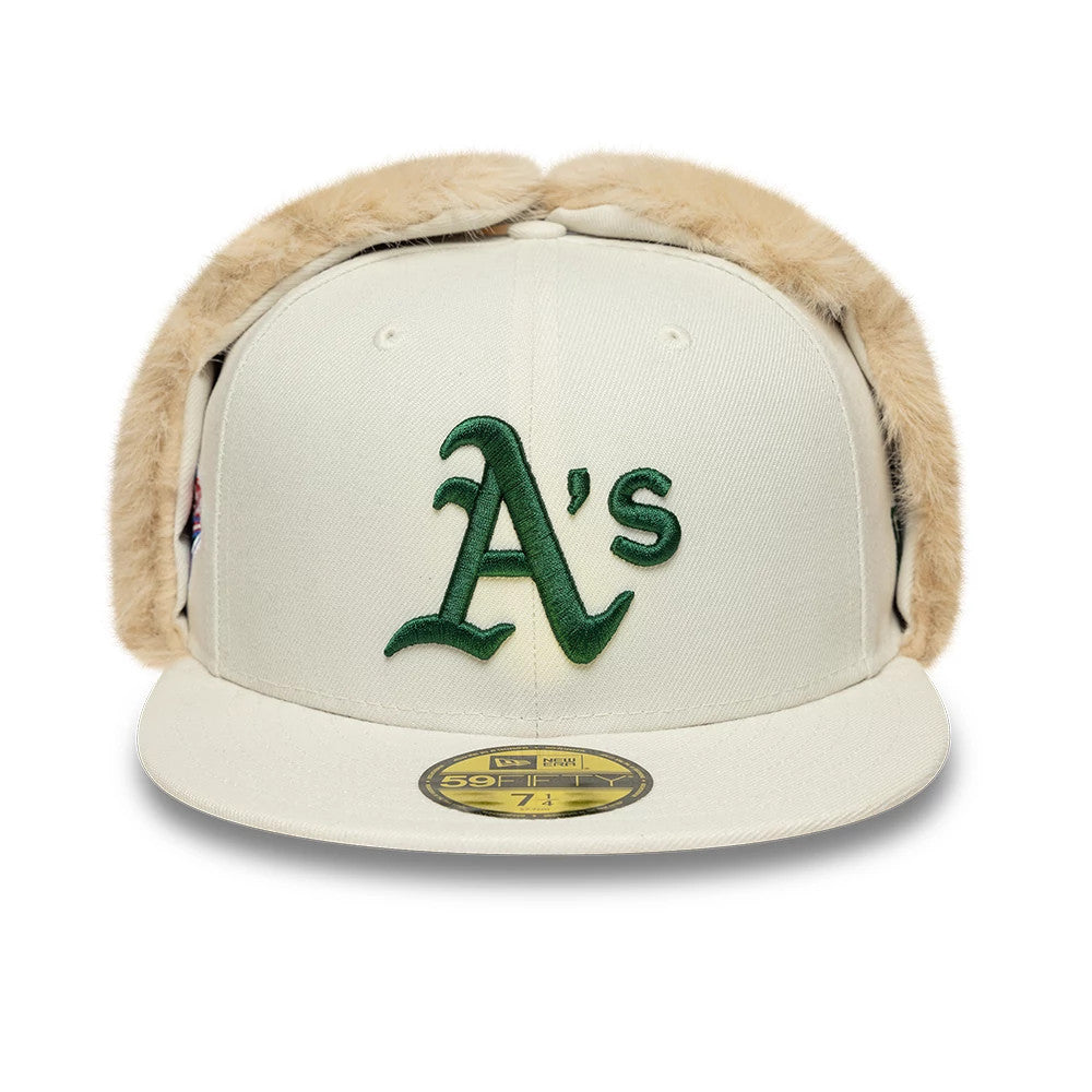 Athletics MLB World Series Cream Dogear New Era 59FIFTY Fitted Cap, front view showing the raised green embroidered Athletics logo on the cream front panel, with furry dogear flaps, a flat cream visor, and a gold 59FIFTY size sticker.