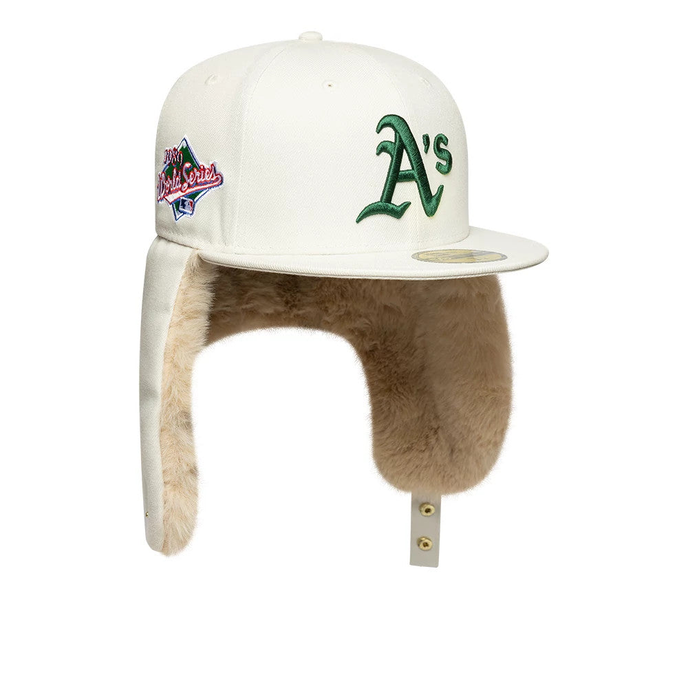 Athletics MLB World Series Cream New Era 59FIFTY Fitted Cap, three-quarter view showing the green A's logo embroidered on the front panel, flat cream visor with a gold 59FIFTY size sticker, and beige plush-lined dogears.