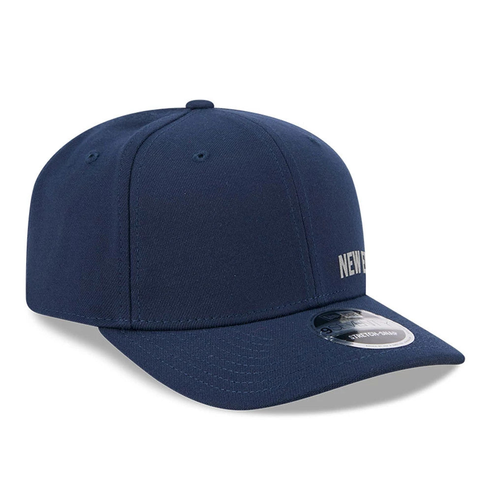 New Era Flawless Dark Blue 9SEVENTY Stretch Snap Adjustable Cap, three-quarter view with a flat New Era script embroidered on the front panel, curved visor, and 9SEVENTY size sticker on dark blue fabric.