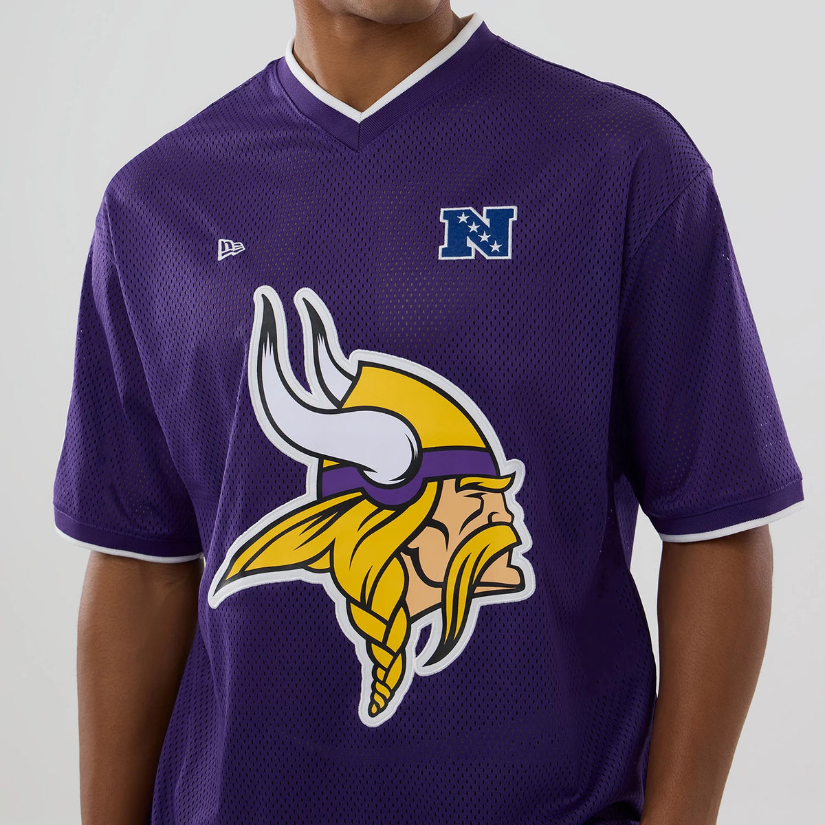 New Era Minnesota Vikings NFL Mesh Purple Oversized T-Shirt, front view showing a large Viking head graphic in yellow and white on the chest, with an embroidered New Era logo on the left side and an N emblem on the right.
