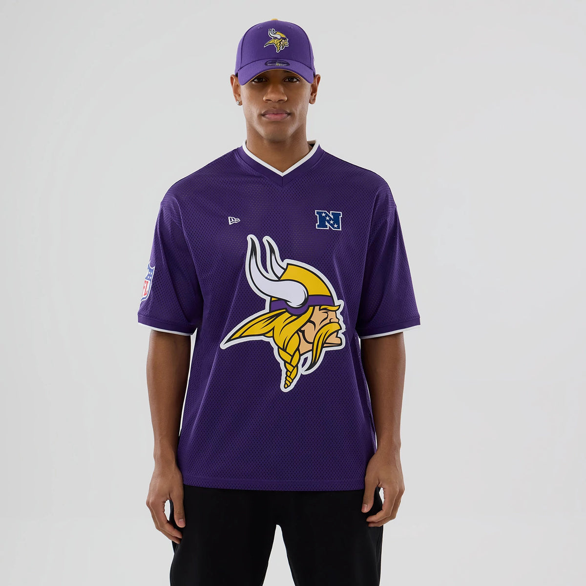 New Era Minnesota Vikings NFL Mesh Purple Oversized T-Shirt, front view on-model featuring a large yellow and white Viking logo centred on the chest, embroidered New Era logo above and a blue NFC emblem on the right side.