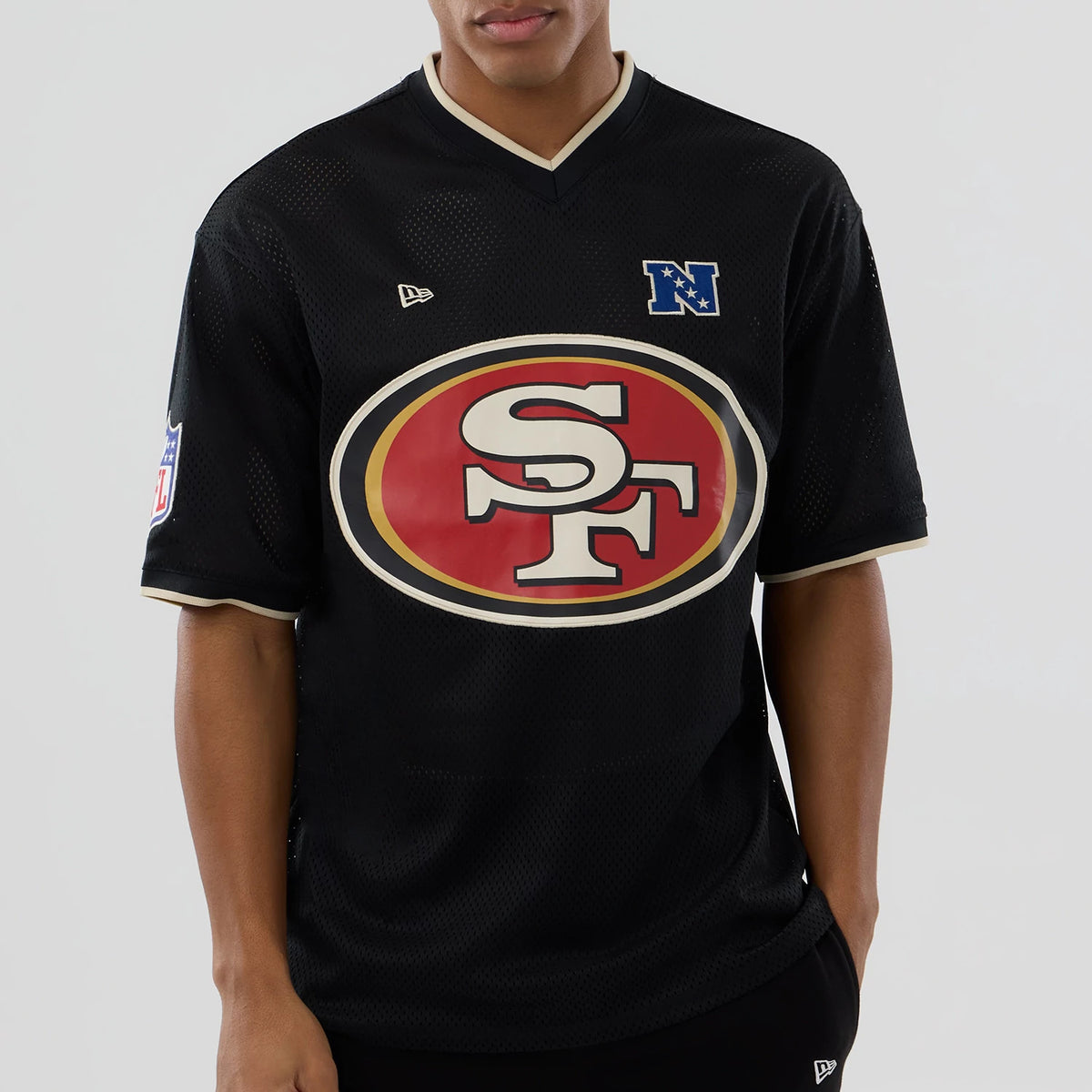 New Era San Francisco 49ers NFL Mesh Black Oversized T-Shirt, front view on a model showing a large red SF logo centred on the chest, a blue embroidered N logo on the right shoulder, and the New Era logo on the left.