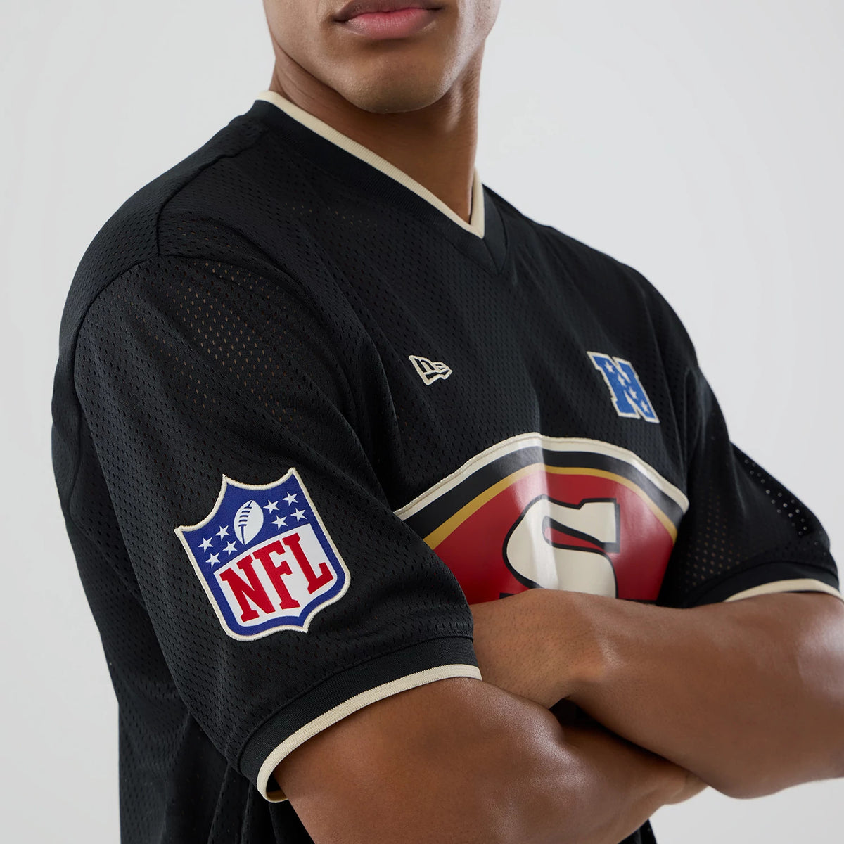 New Era San Francisco 49ers NFL Mesh Black Oversized T-Shirt, front view on a model showing the large red and gold 49ers logo across the chest, embroidered New Era logo on the upper chest, and NFL patch on the sleeve.