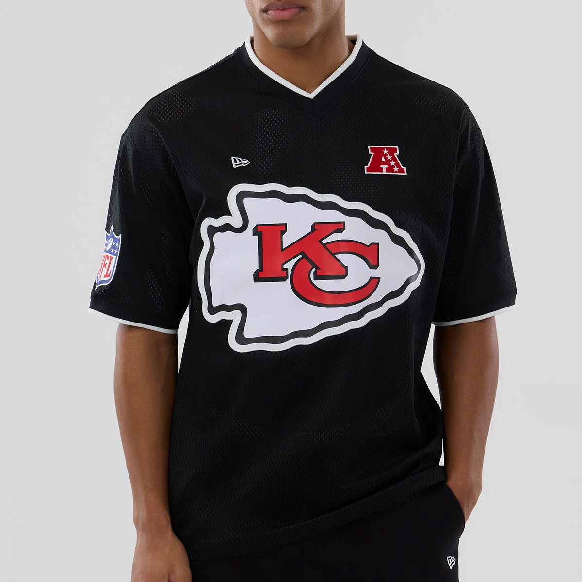 New Era Kansas City Chiefs NFL Mesh Black Oversized T-Shirt, front view on-model showcasing a large white and red KC logo across the chest, an embroidered New Era flag logo on the left chest, and an NFL patch on the right sleeve.