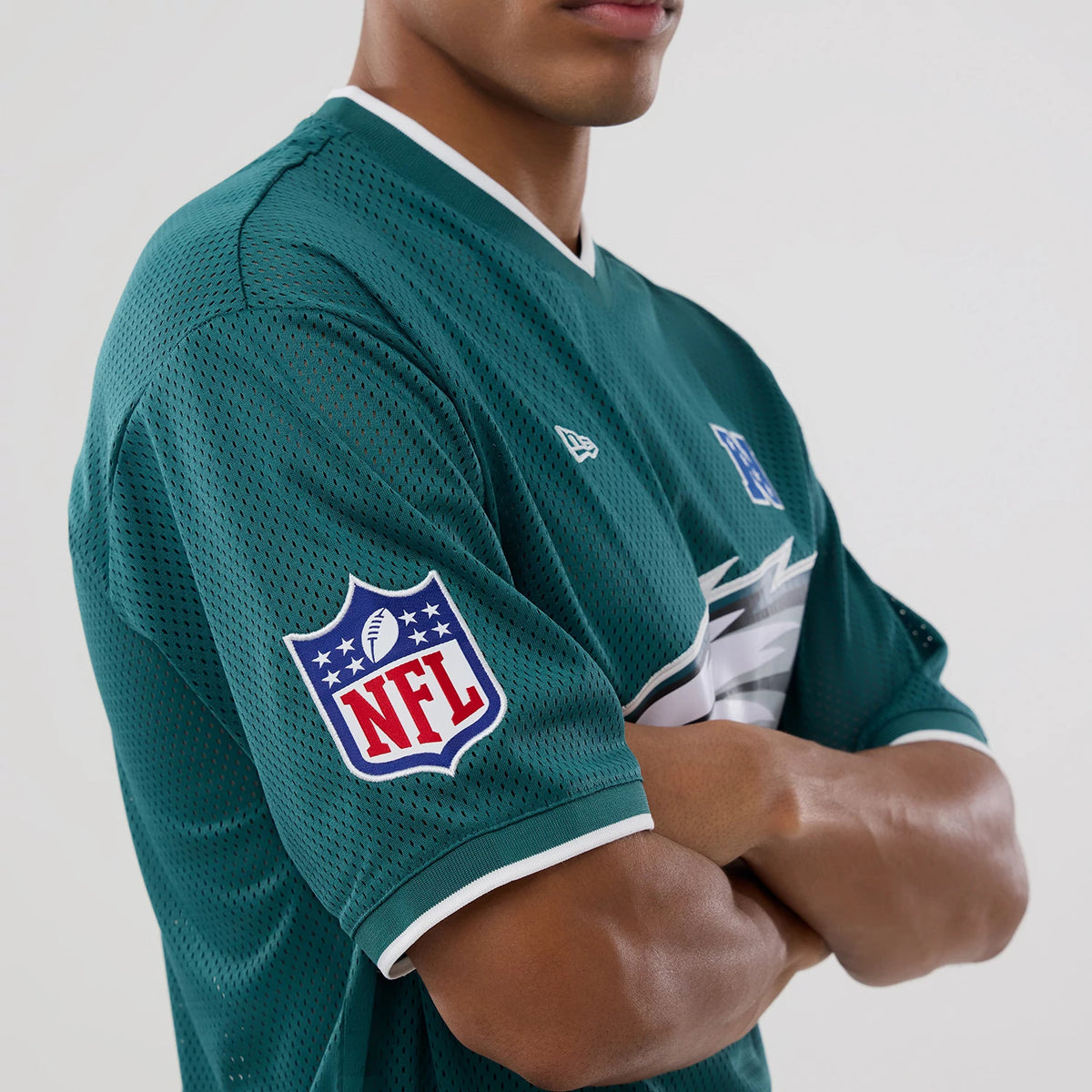 New Era Philadelphia Eagles NFL Mesh Dark Green Oversized T-Shirt, three-quarter view on-model showing an embroidered NFL shield logo on the sleeve, a raised eagle logo on the chest, and a white embroidered New Era logo on the right shoulder.