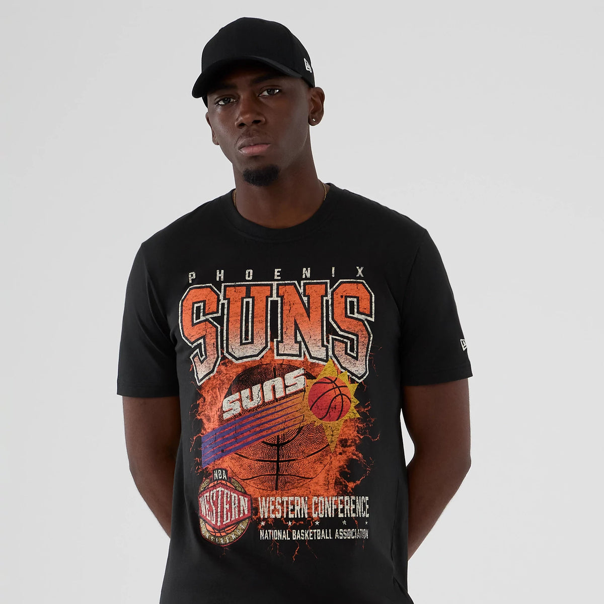 New Era Phoenix Suns NBA Hardwood Classic Black T-Shirt, front view showing the retro Suns graphic with lettering and a basketball motif, worn by a model styled with a black New Era cap displaying a small embroidered logo.