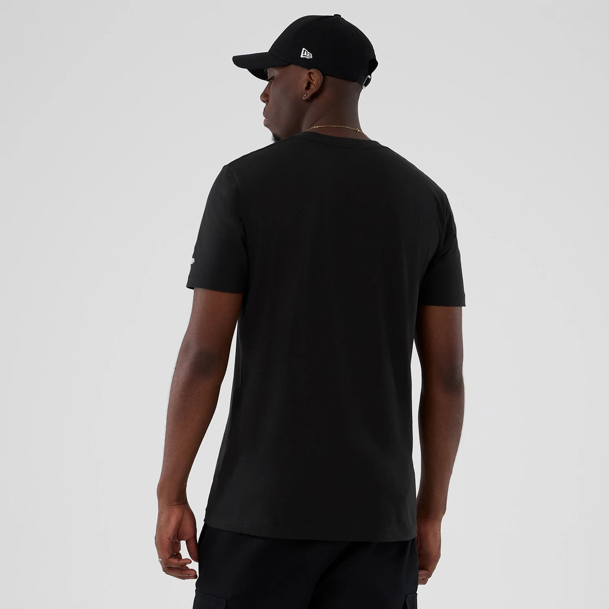 New Era Toronto Raptors NBA Hardwood Classic Black T-Shirt, back view on a model with a matching cap showing the plain black back design and a embroidered New Era logo on the sleeve.