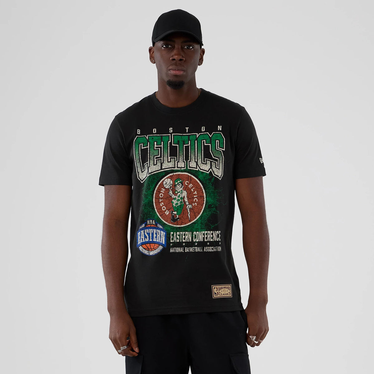 New Era Boston Celtics NBA Hardwood Classic Black T-Shirt, front view on-model featuring a large Celtics graphic with a green and white motif, Eastern Conference basketball emblem below and a rectangular label at the hem.