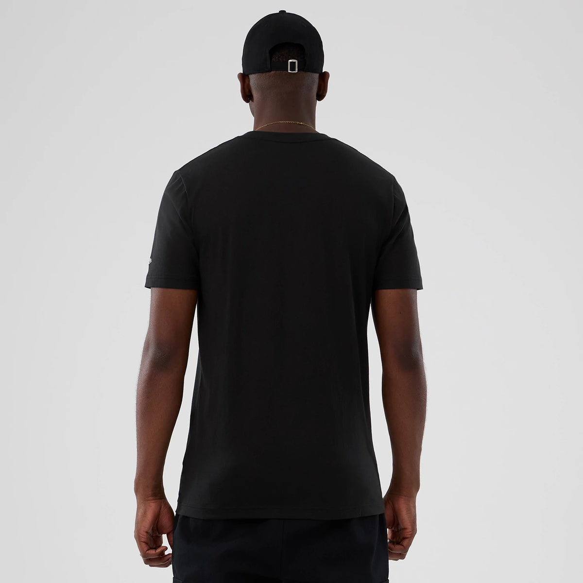 New Era Milwaukee Bucks NBA Hardwood Classic Black T-Shirt, back view on a model styled with a black cap, showing a plain black back with short sleeves and a embroidered New Era logo on the left sleeve.
