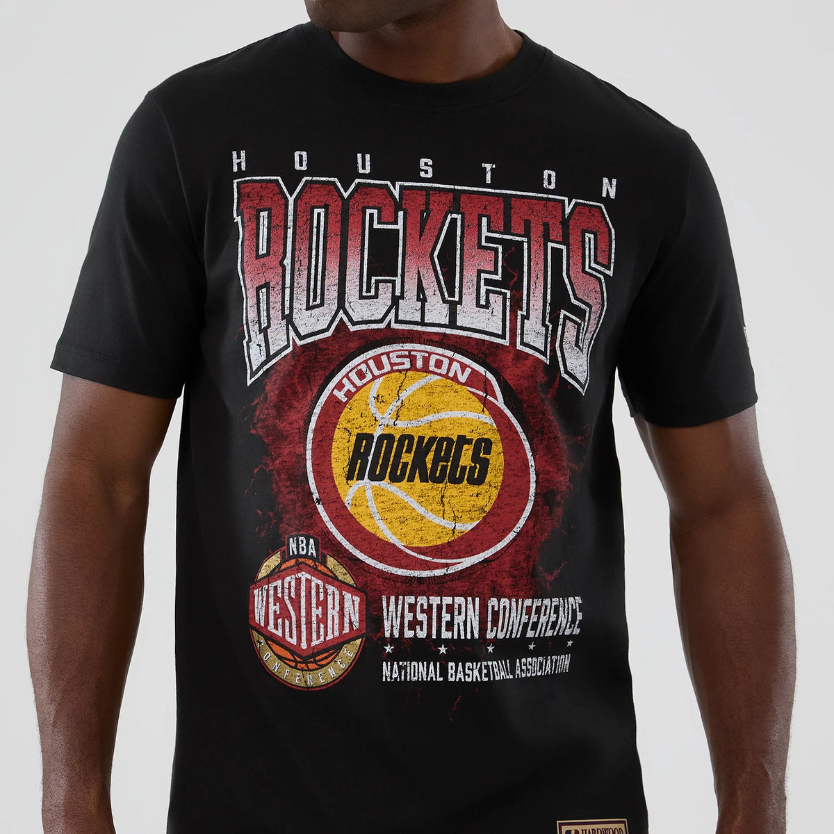 New Era Houston Rockets NBA Hardwood Classic Black T-Shirt, front view showing large red and yellow graphic with Rockets lettering across the chest and a smaller NBA Western Conference emblem below, worn by a model.