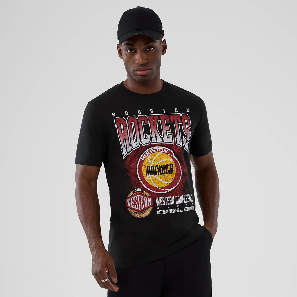 New Era Houston Rockets NBA Hardwood Classic Black T-Shirt, front view on a model with a black cap, featuring red and yellow Rockets graphics across the chest along with the team and conference details printed in white and red.