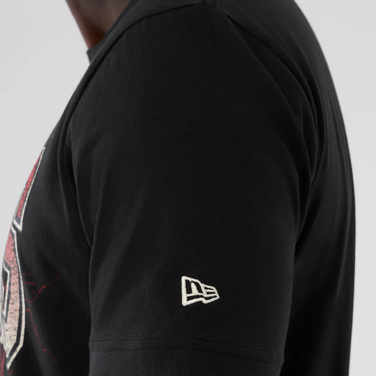 New Era Detroit Pistons NBA Hardwood Classic Black T-Shirt, side view showing the white embroidered New Era logo on the left sleeve and part of a graphic in red and white on the upper chest.