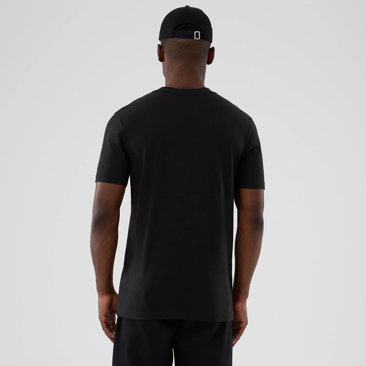 New Era Dallas Mavericks NBA Hardwood Classic Black T-Shirt, back view on-model showing the simple black design with a crew neck and short sleeves, paired with a coordinating black cap with an embroidered logo above the adjustable strap.