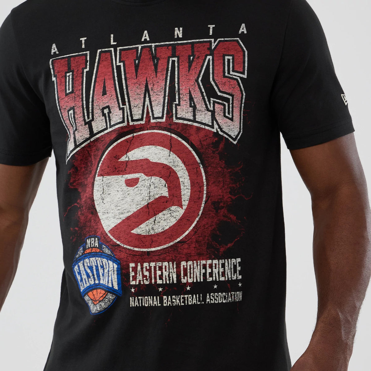 New Era Atlanta Hawks NBA Hardwood Classic Black T-Shirt, front view showing a large distressed Hawks graphic in red and white on the chest, with the Eastern Conference logo below and an embroidered New Era logo on the sleeve.