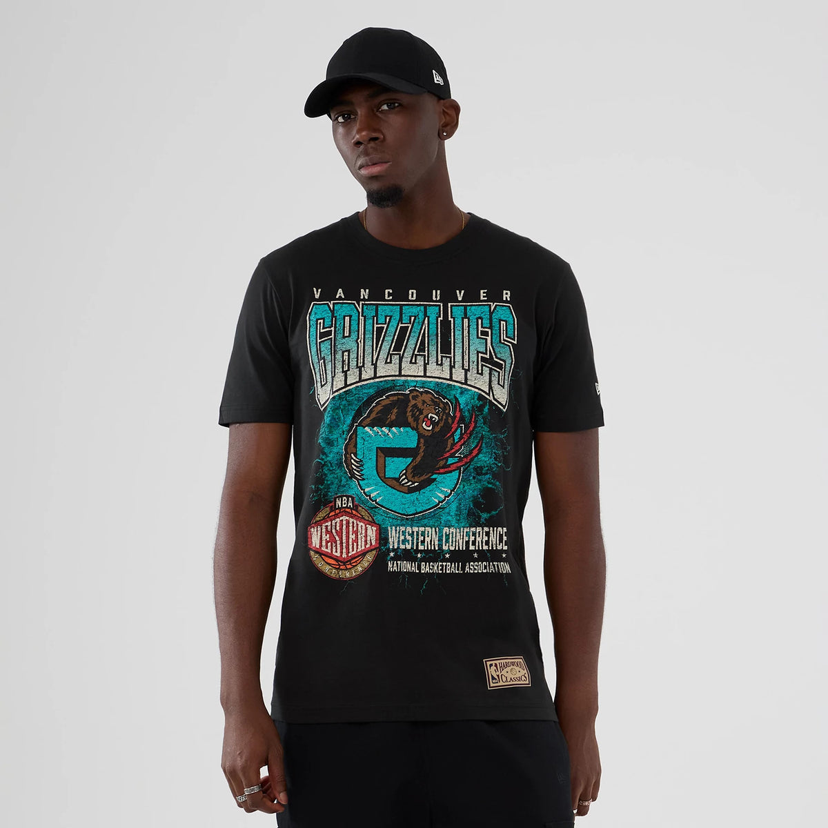New Era Vancouver Grizzlies NBA Hardwood Classic Black T-Shirt, front view on-model featuring a graphic of the Grizzlies logo and lettering on the chest, with Western Conference and NBA logos printed below, paired with a black New Era cap.