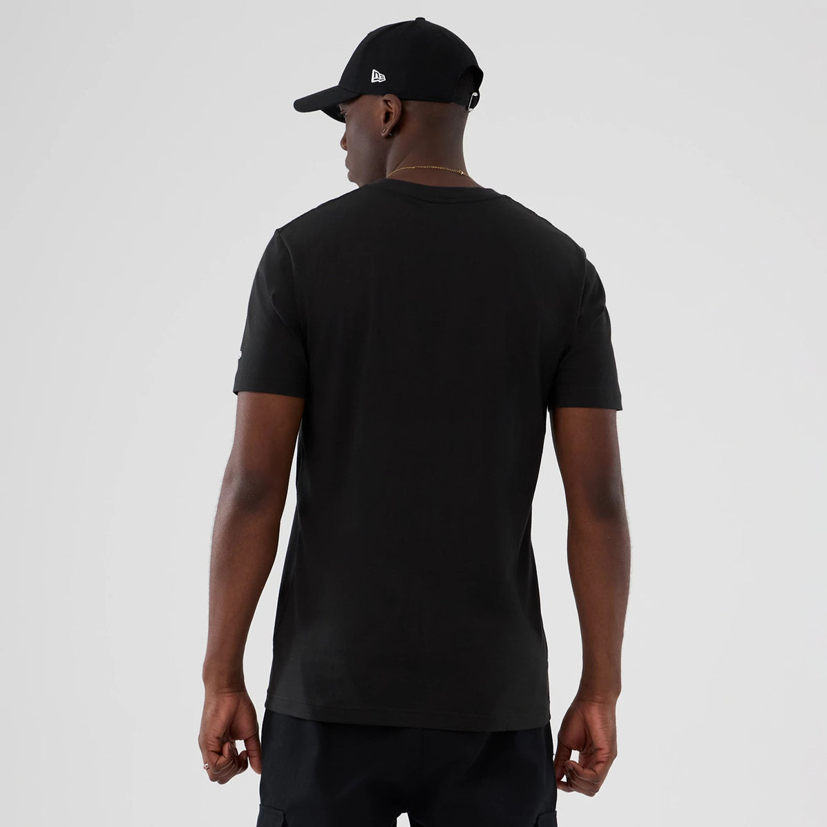 New Era Vancouver Grizzlies NBA Hardwood Classic Black T-Shirt, back view on a model styled with a black cap, showing the clean black back with short sleeves and the New Era logo embroidered on the side of the cap.