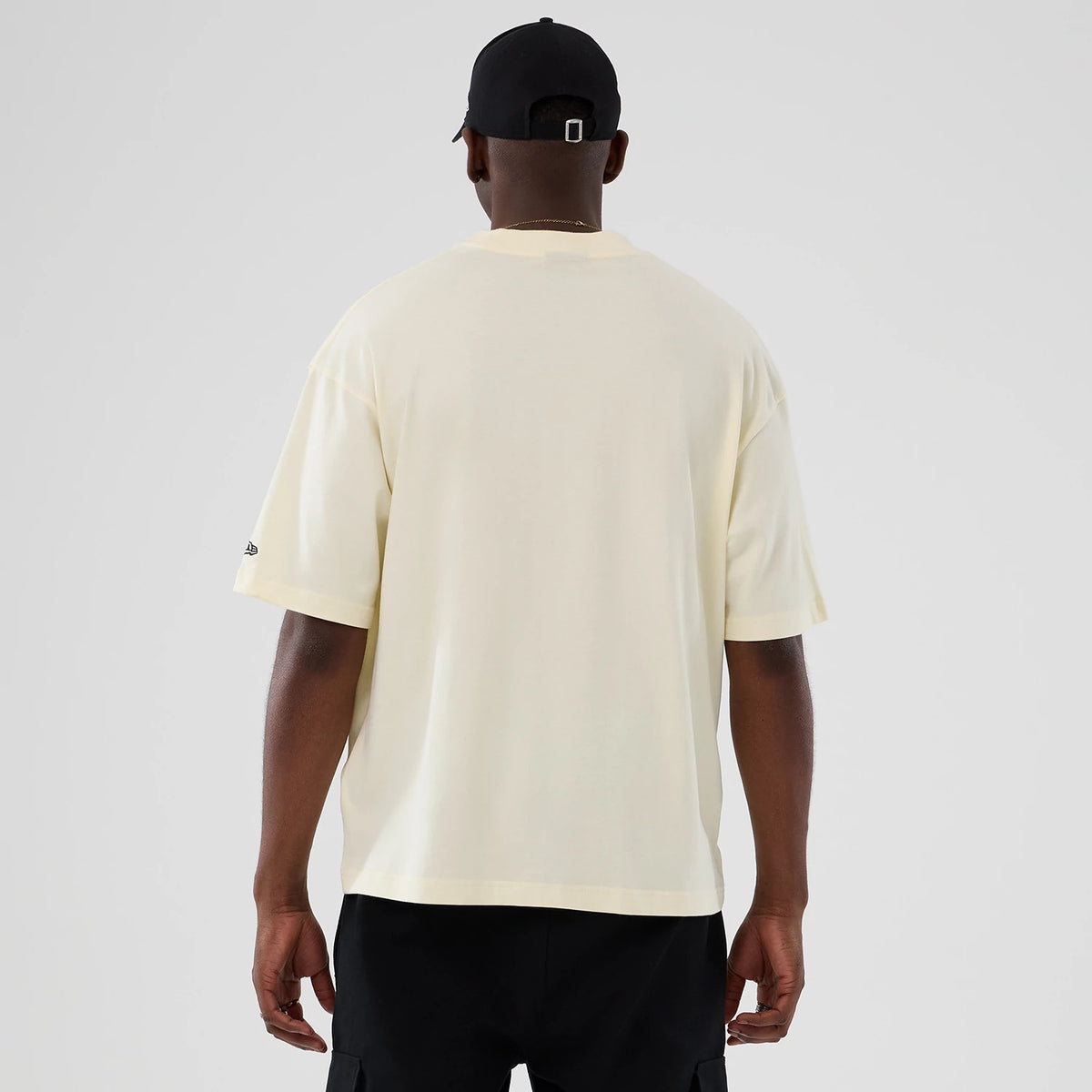 New Era Chicago Bulls NBA Hardwood Classic Cream T-Shirt, back view on a model with a black cap, showing the plain cream back with short sleeves and an embroidered New Era logo on the left sleeve.