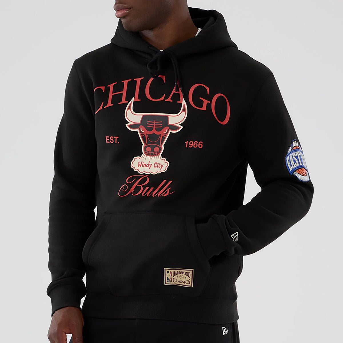 New Era Chicago Bulls NBA Hardwood Classic Black Pullover Hoodie, front view showing the red Chicago Bulls logo and lettering on the chest, an embroidered NBA logo patch on the left sleeve, and a Hardwood Classics patch above the ribbed hem.