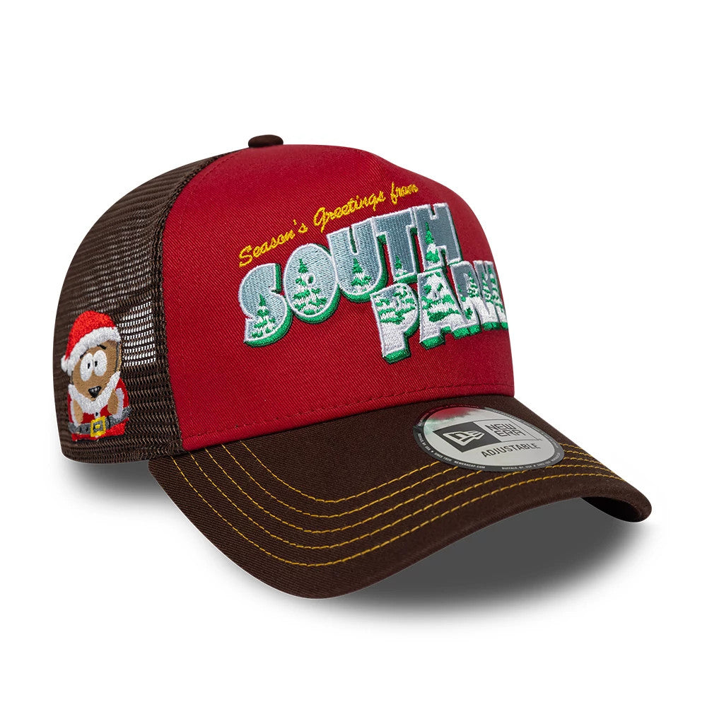 South Park Dark Red New Era 9FORTY A-Frame Trucker Adjustable Cap, three-quarter view showing colourful South Park logo and Season’s Greetings text on the red front panel, with a brown curved visor and New Era 9FORTY size sticker.