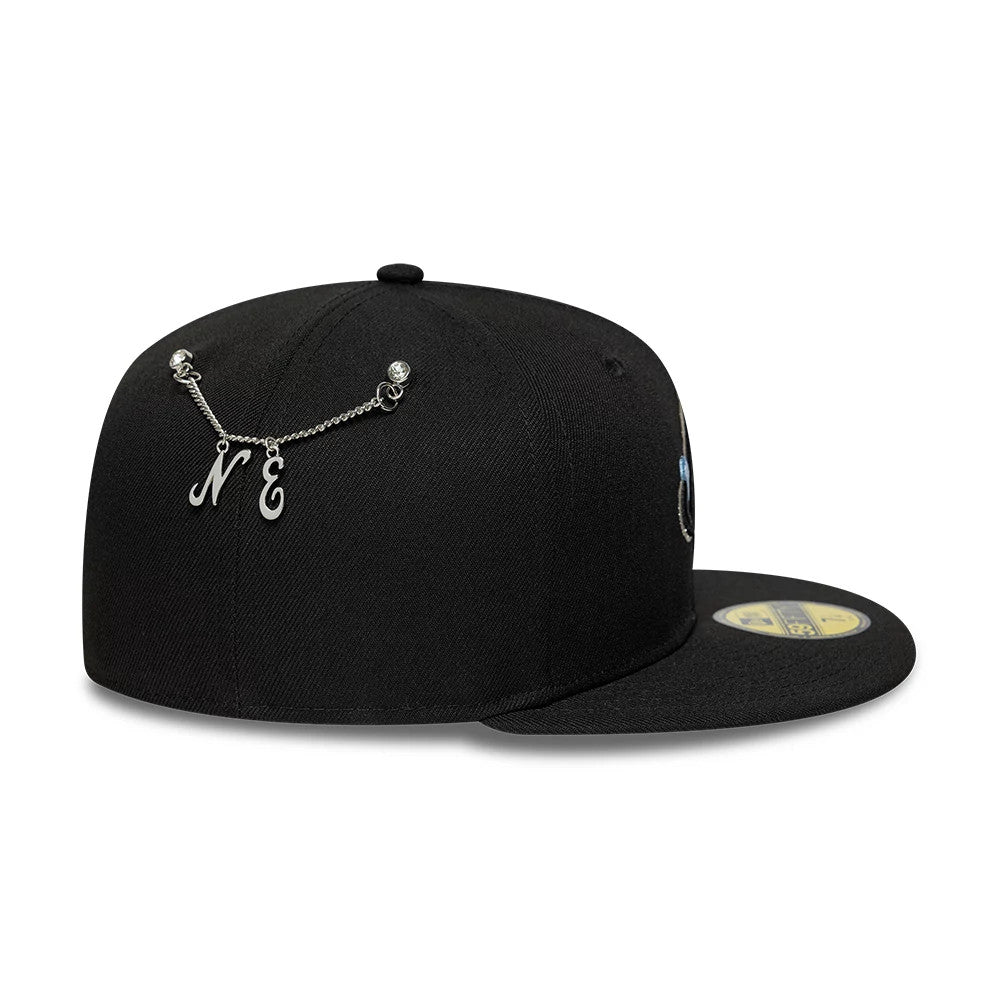 New Era Snow Icon Black 59FIFTY Fitted Cap, side view showing a chain with N and E charms across the back panels, a structured black crown, and a flat black visor with a gold 59FIFTY size sticker on top.