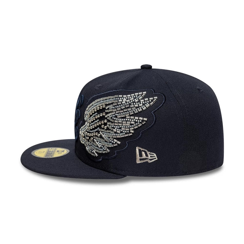 New Era Beaded Wings Navy 59FIFTY Fitted Cap, side view with a detailed beaded wing design on the front panel against a structured navy crown, featuring the New Era flag logo embroidered on the left side and a gold 59FIFTY size sticker on the visor.