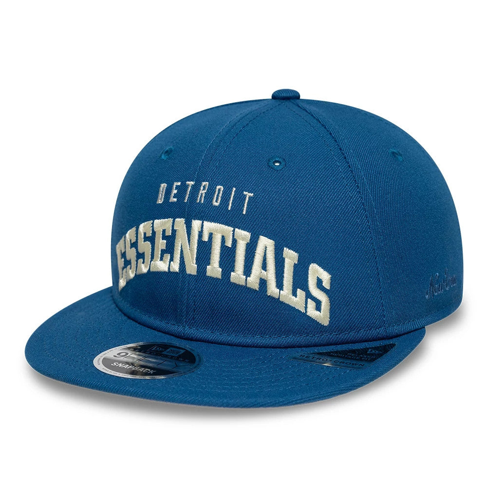Detroit Lions Fear Of God x NFL Blue Retro Crown New Era 9FIFTY Adjustable Cap, front three-quarter view showing cream embroidered Detroit Essentials text on the structured blue crown and black 9FIFTY size sticker on the blue visor.