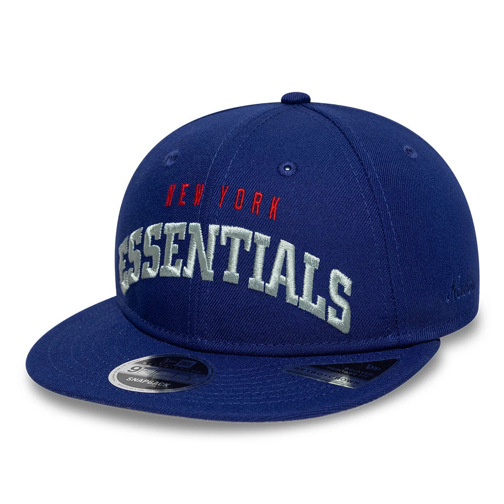 New York Giants Fear Of God x NFL Dark Blue Retro Crown New Era 9FIFTY Adjustable Cap, three-quarter view showing red New York and white Essentials embroidery on the front panel, with a dark blue flat visor and a 9FIFTY size sticker.