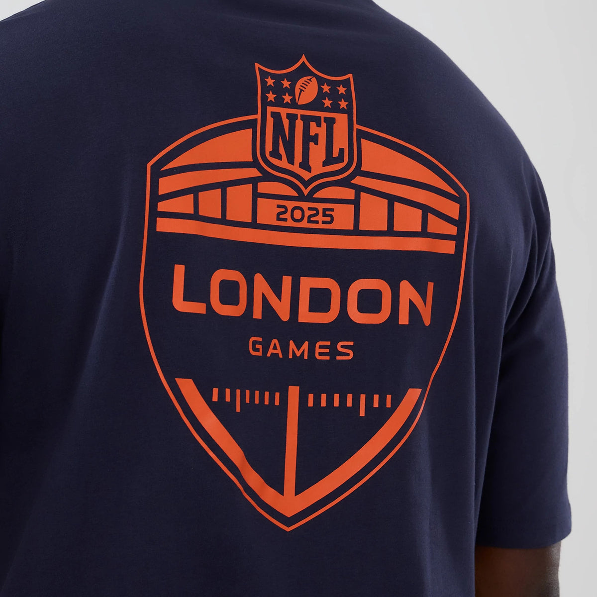 New Era Denver Broncos NFL International Series Games 2025 Navy Oversized T-Shirt, back view showing a large orange printed NFL 2025 London Games emblem centred on the upper back of the navy fabric.