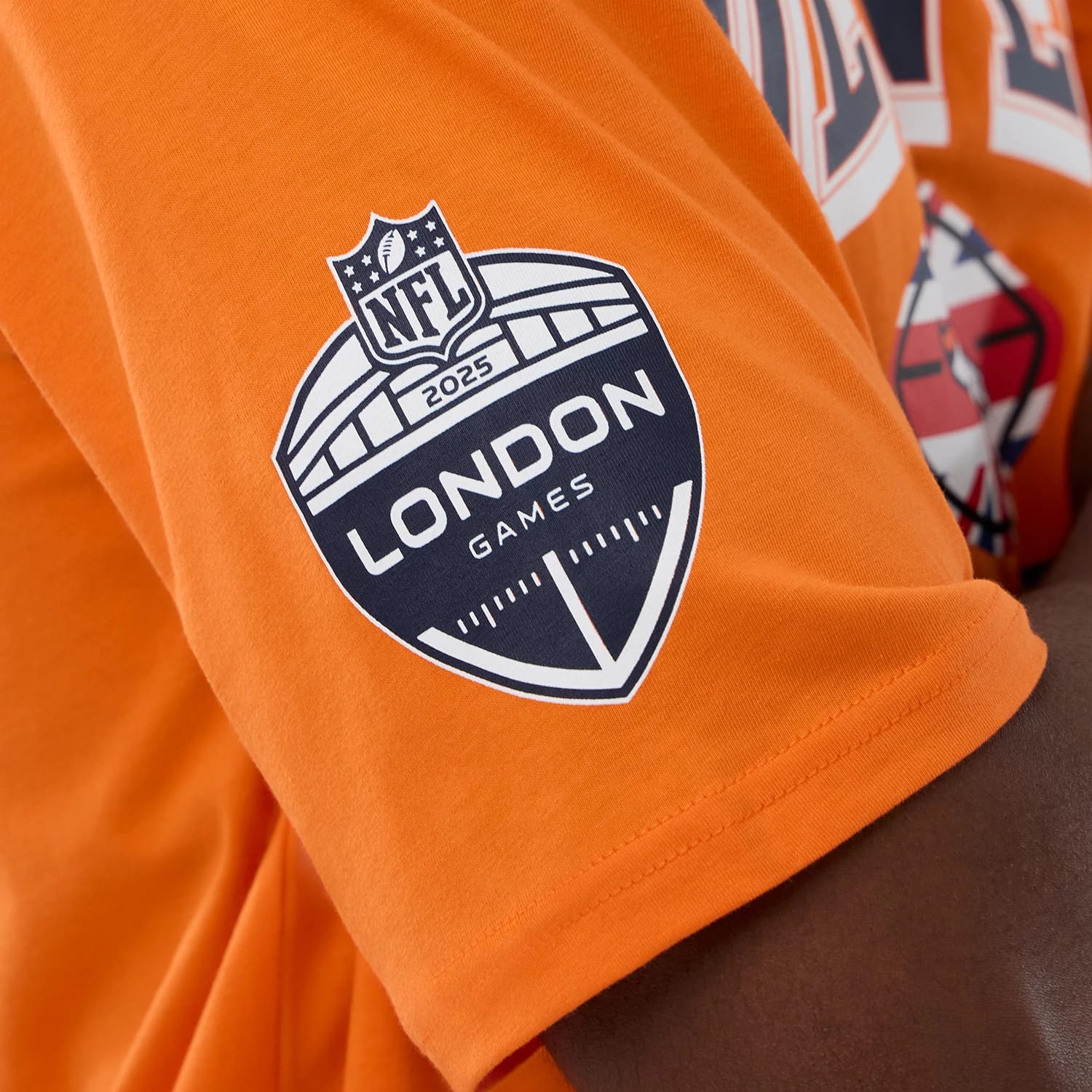 The Male model is wearing Denver Broncos NFL International Series Games 2025 Orange Oversized T-Shirt 4