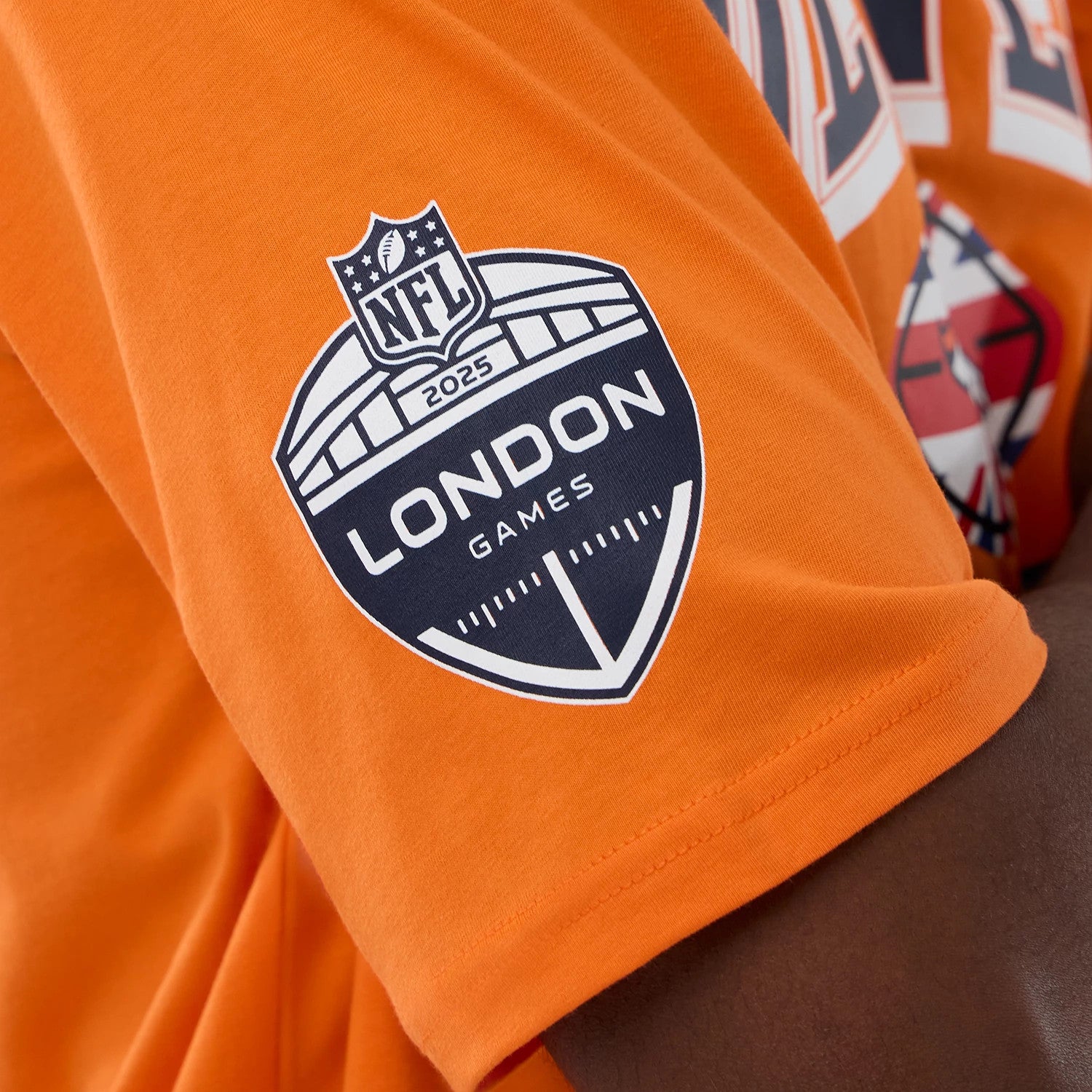The Male model is wearing Denver Broncos NFL International Series Games 2025 Orange Oversized T-Shirt 4