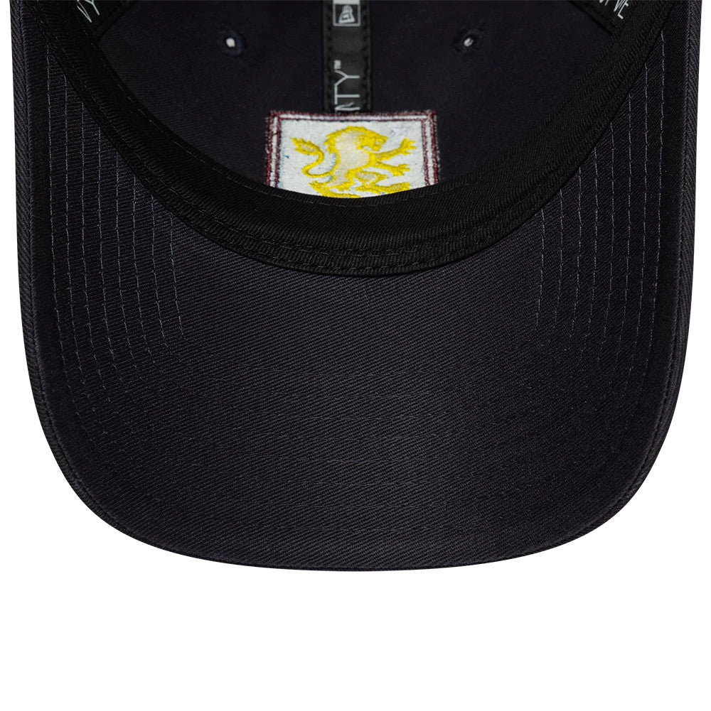 Aston Villa FC Core Navy New Era 9TWENTY Cap, inside view showing a yellow lion graphic patch beneath the black undervisor, with black sweatband and branded taping running along the inner crown.