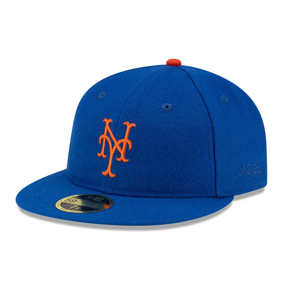New York Mets FOG X MLB Blue Retro Crown New Era 59FIFTY Fitted Cap, three-quarter view showing the orange embroidered NY logo on the front panel, blue flat visor with a gold 59FIFTY size sticker, and red top button.