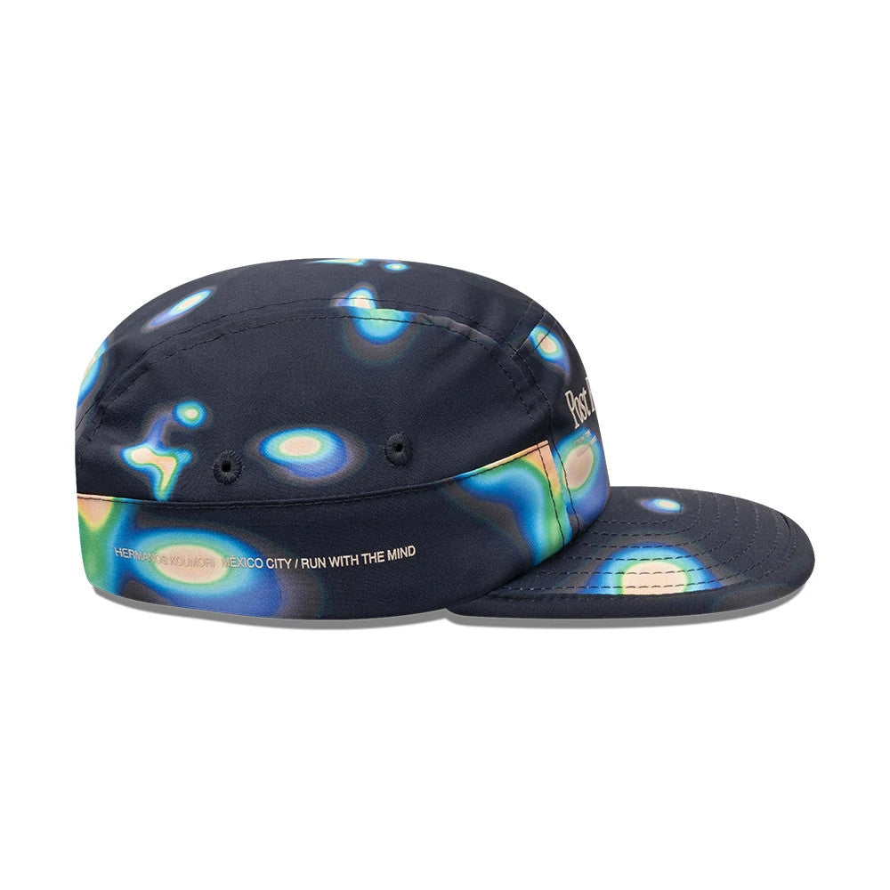 Hermanos Koumori x New Era Navy Camper Cap, side view showing multicoloured abstract pattern across the structured crown and visor, with embroidered text HERMANOS KOUMORI MEXICO CITY/RUN WITH THE MIND on the side panel.