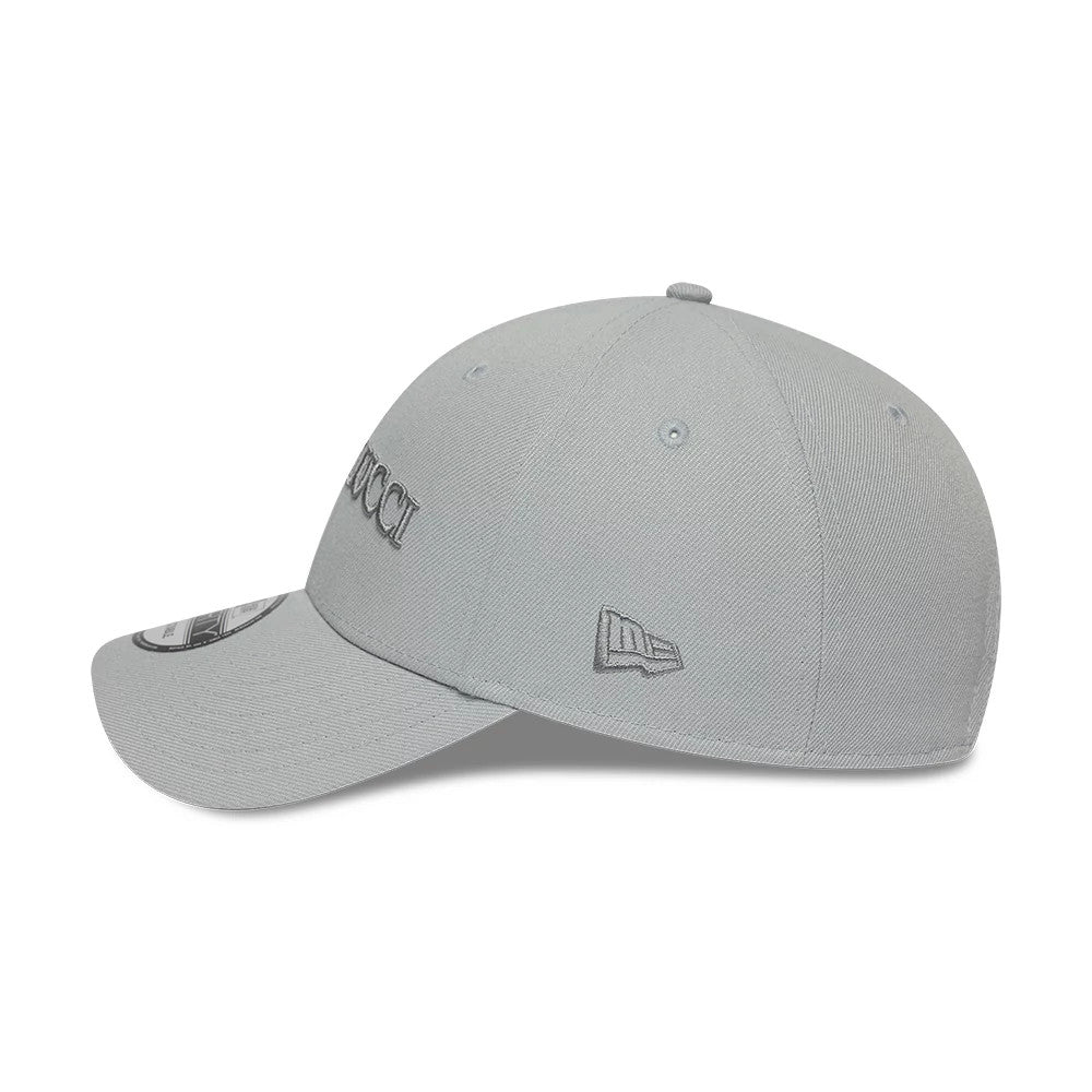 Colucci X New Era Grey 9FORTY Adjustable Cap, side view showing the grey embroidered Colucci logo on the front panel, New Era flag logo on the left side, curved visor with 9FORTY size sticker, and matching top button.