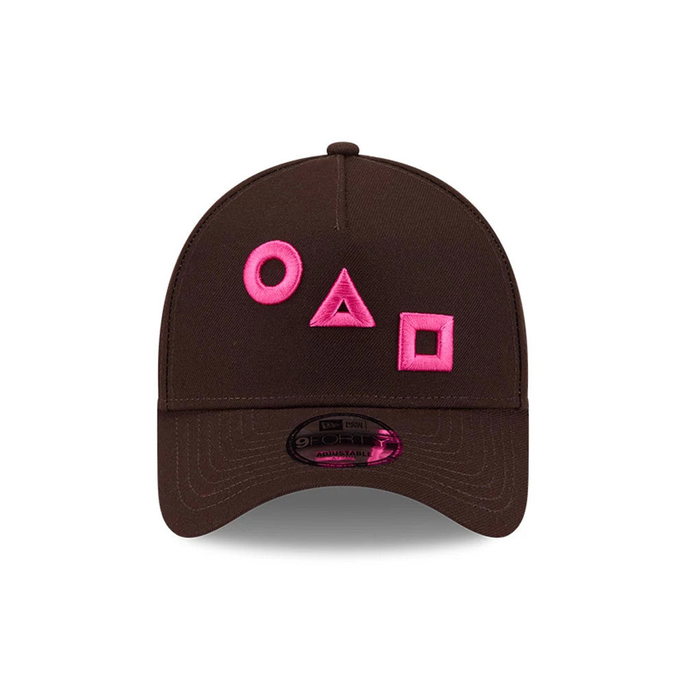 Netflix Squid Game Shapes Dark Brown New Era 9FORTY A-Frame Adjustable Cap, front view showing pink embroidered circle, triangle, and square shapes on the dark brown structured crown, with a 9FORTY size sticker on the curved visor.