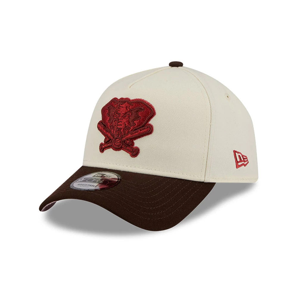 Athletics MLB City Script Cream New Era 9FORTY A-Frame Adjustable Cap, three-quarter view showing the raised red embroidered elephant and crossed bats logo on the front cream panel, brown curved visor, and red New Era flag logo on the left side.