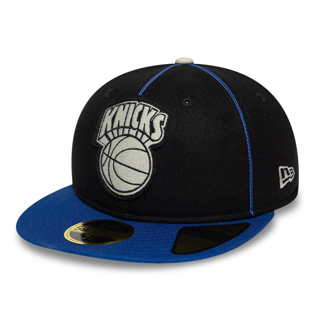 New York Knicks NBA Felt Logo Dark Blue Retro Crown New Era 59FIFTY Fitted Cap, front view showing the grey embroidered Knicks logo on the black crown, a contrasting blue visor, and the gold 59FIFTY size sticker on the top.