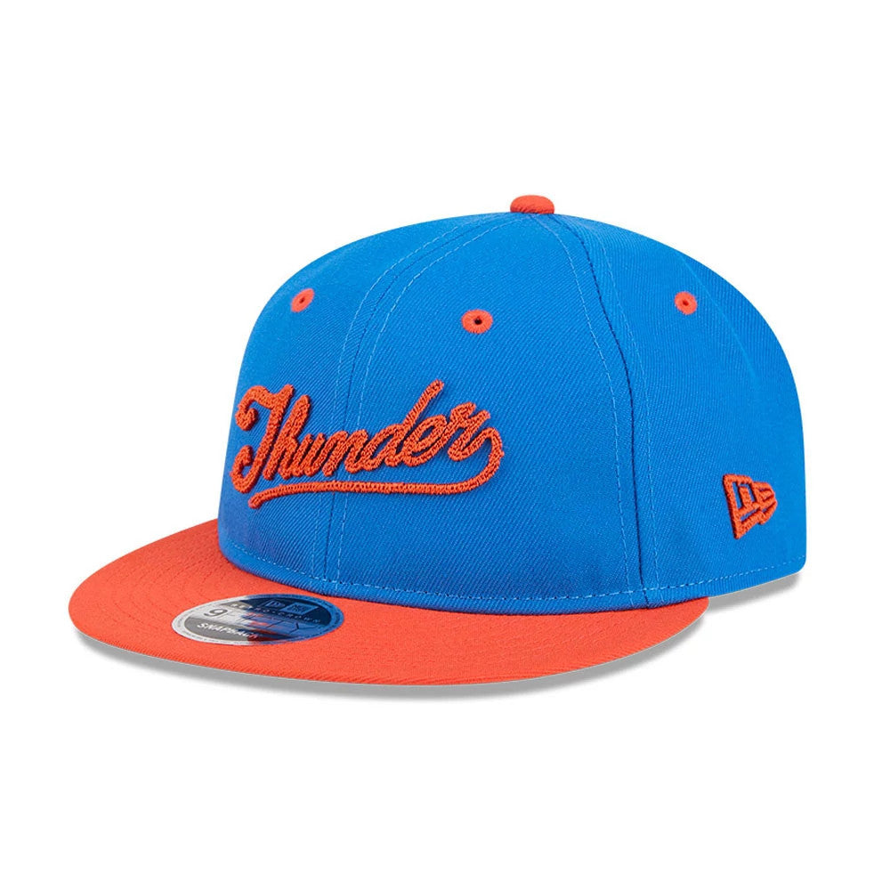 OKC Thunder NBA Chainstitch Script Blue Retro Crown New Era 9FIFTY Adjustable Cap, three-quarter view showing the orange chainstitch Thunder script on the front panel, orange flat visor with a 9FIFTY size sticker, and orange eyelets and top button.