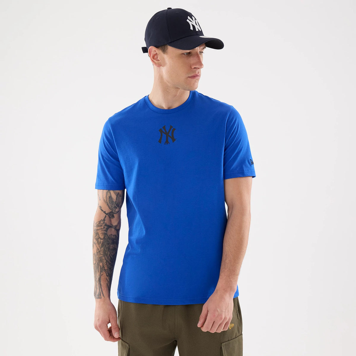 New Era New York Yankees MLB Blue T-Shirt, front view on a model also wearing a Yankees cap, featuring a large printed Yankees logo centred on the chest, a small embroidered New Era logo on the left sleeve, and short sleeves.