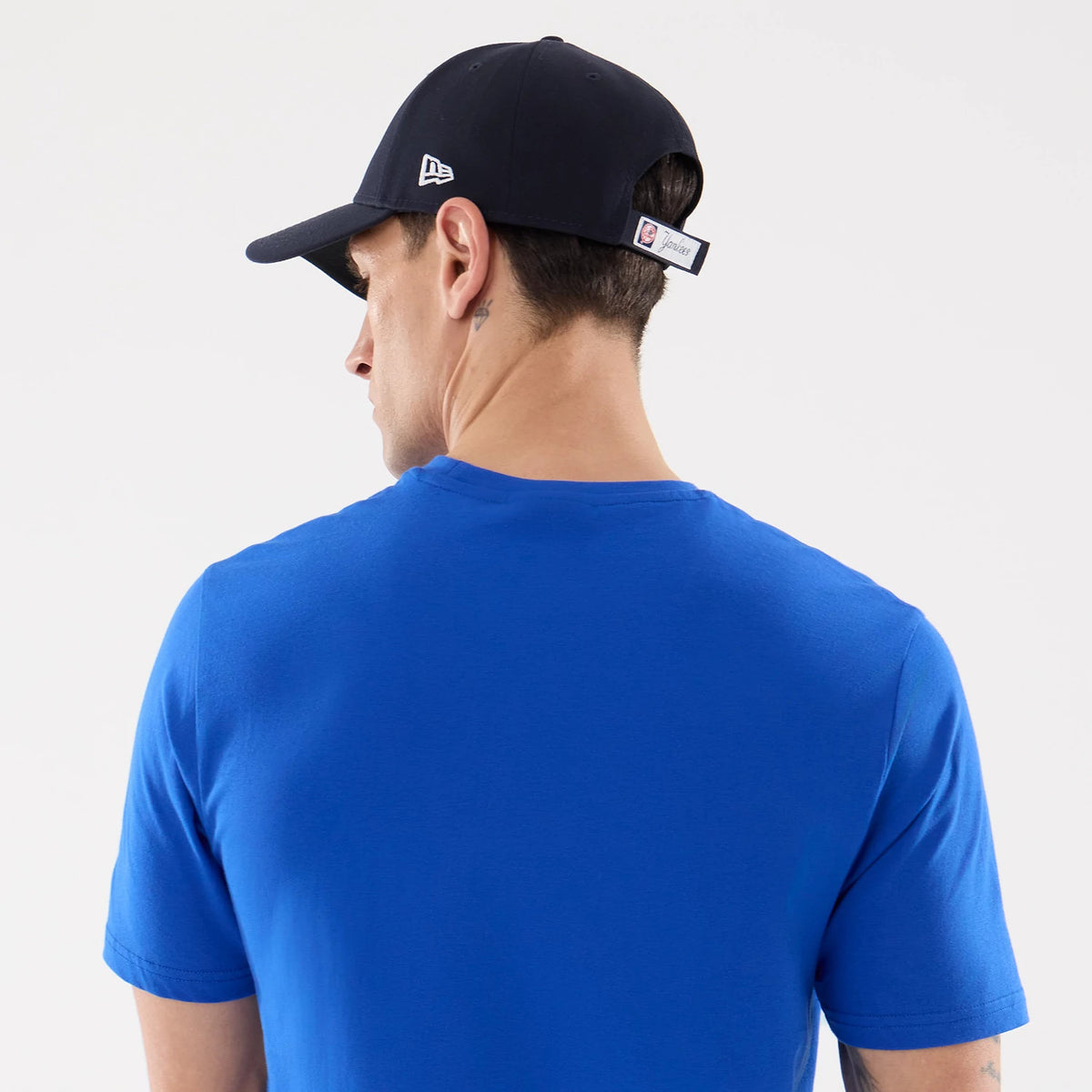 New Era New York Yankees MLB Blue T-Shirt, back view on a model paired with a navy cap, displaying a clean blue surface and short sleeves, with a small embroidered New Era logo on the side of the cap.