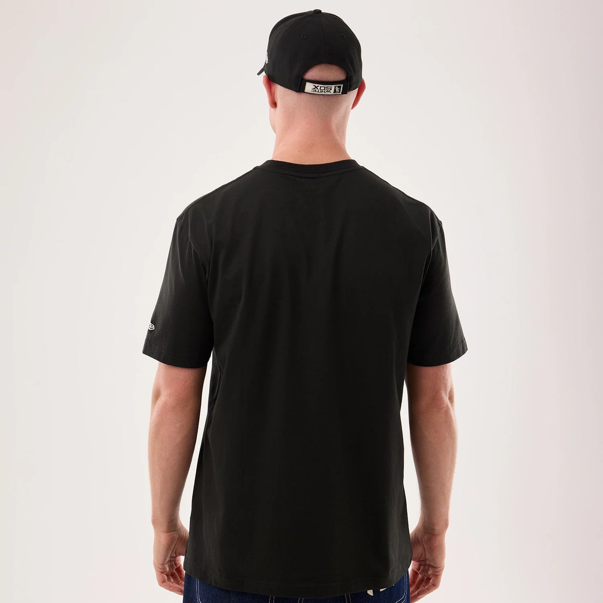 New Era Chicago White Sox MLB Life Graphic Black T-Shirt, back view on a model wearing a matching black cap, showing a plain black back with a small embroidered New Era logo on the left sleeve against a neutral background.