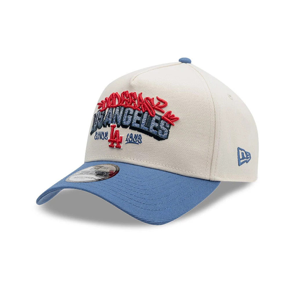 LA Dodgers MLB Tagged Light Beige New Era 9FORTY A-Frame Cap, three-quarter view showing a front panel with red and blue embroidered graffiti-style Los Angeles and LA logo, sky blue curved visor with 9FORTY size sticker.