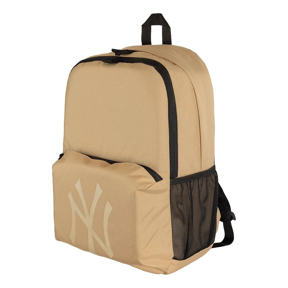 New Era New York Yankees MLB Light Beige Stadium Backpack, three-quarter view highlighting a large front pocket with a debossed Yankees logo, a mesh side pocket, and a black zip closure running along the top edge with a carry handle on top.