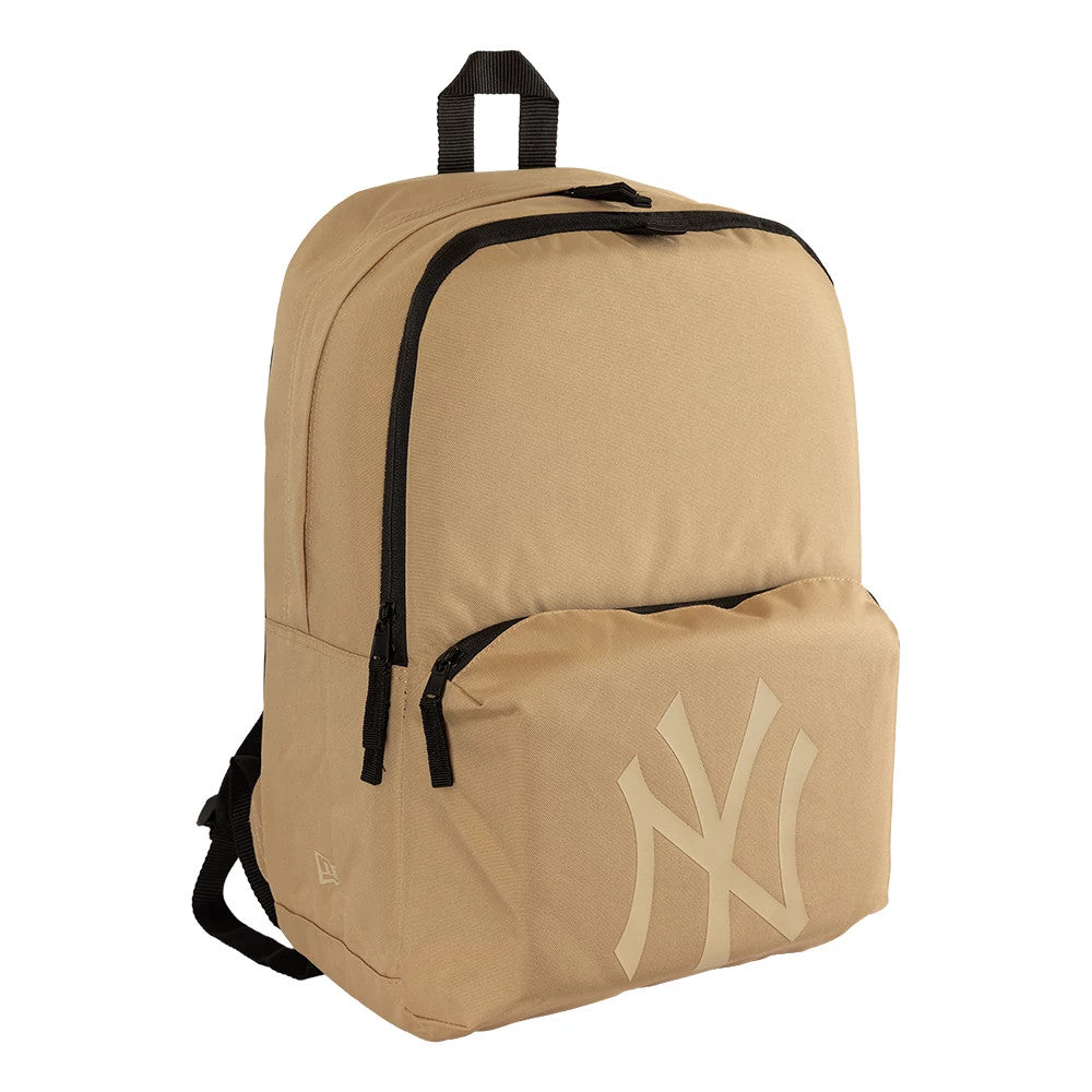 New Era New York Yankees MLB Light Beige Stadium Backpack, three-quarter view showing the spacious light beige body with a large front pocket, a black zip closure on top, and an embossed New York Yankees logo prominently displayed on the pocket.