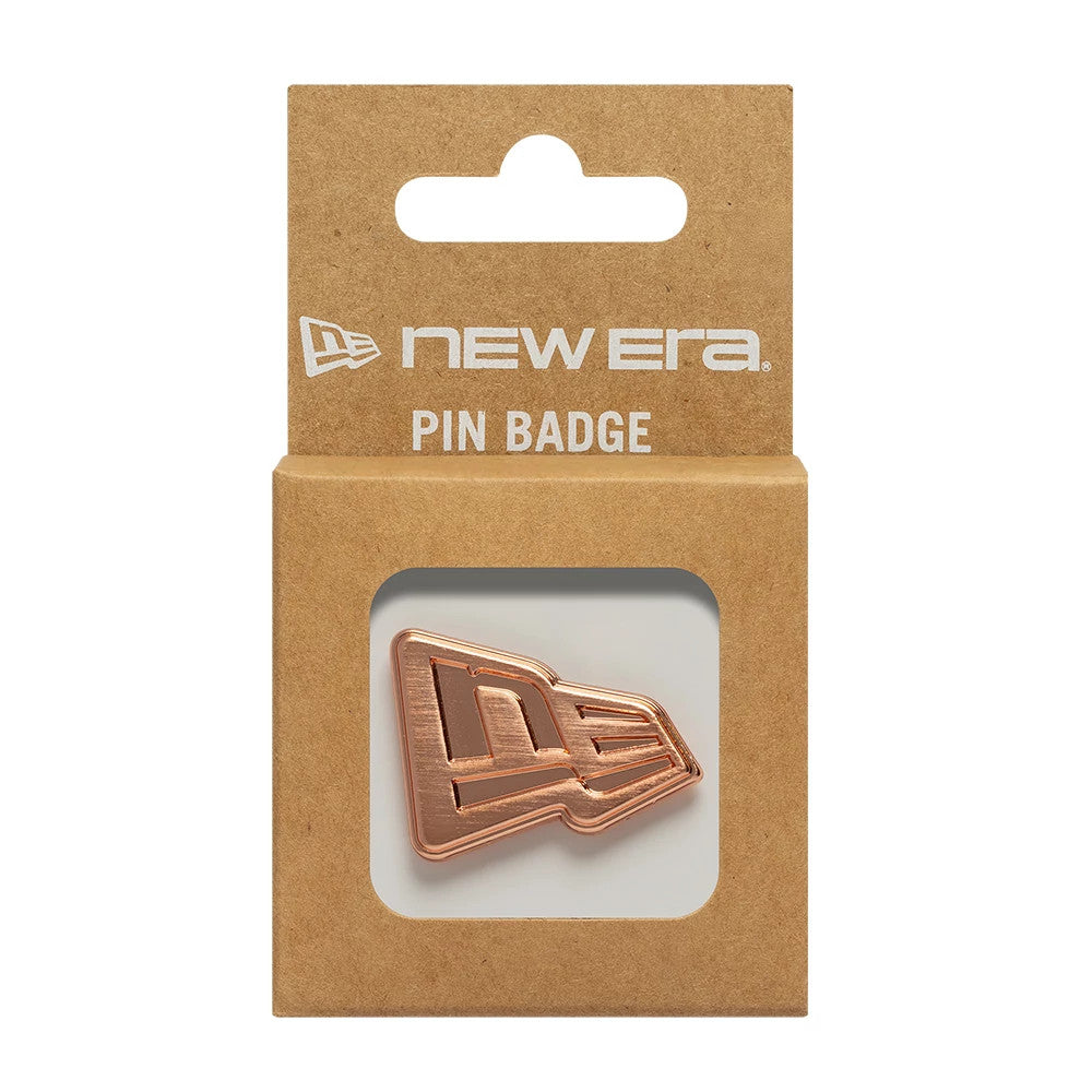 New Era Flag Rose Gold Pin Badge, front view displaying a rose gold debossed New Era flag logo pin set inside a brown cardboard packaging, with white New Era branding and PIN BADGE text printed above the cut-out window.
