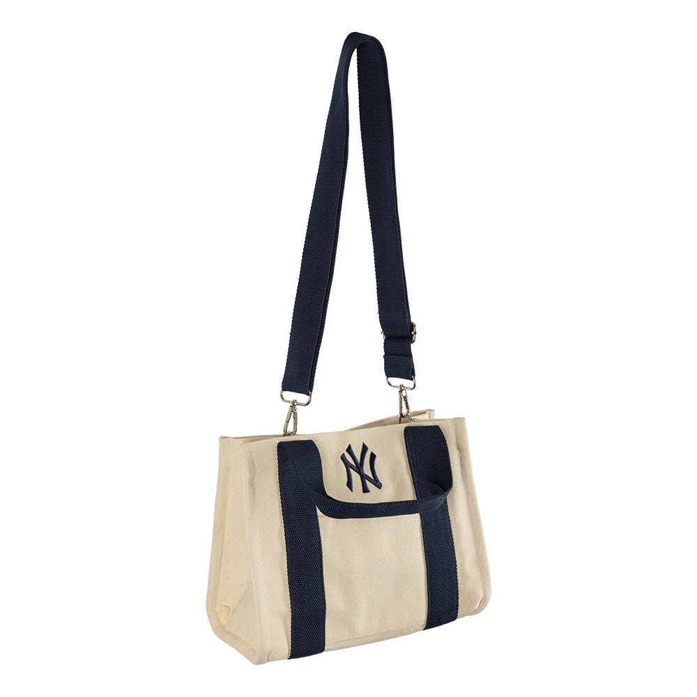 New Era New York Yankees MLB Light Beige & Navy Tote Bag, side view featuring a light beige body with navy blue embroidered New York Yankees logo on the front, navy blue straps running vertically down the sides.