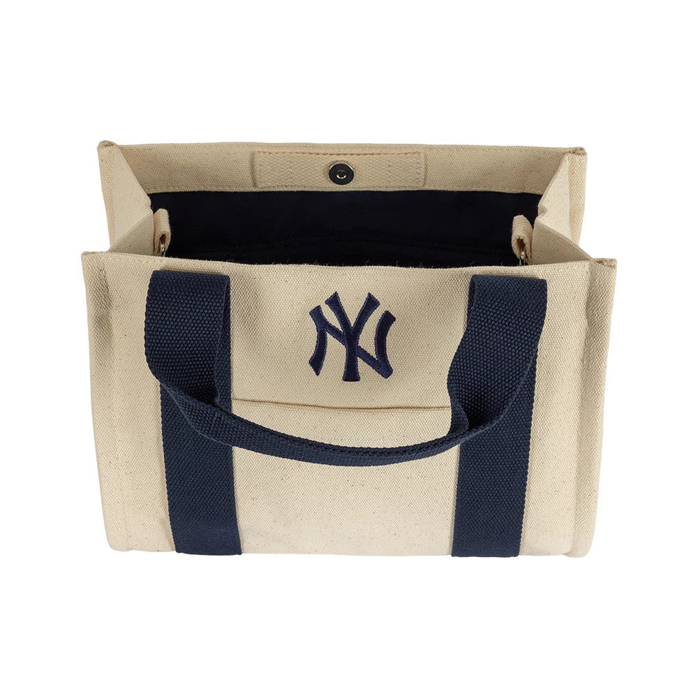 New Era New York Yankees MLB Light Beige & Navy Tote Bag, open view showing the spacious interior with a snap button closure, navy carrying handles running down the front, and an embroidered NY logo centred on the beige exterior.