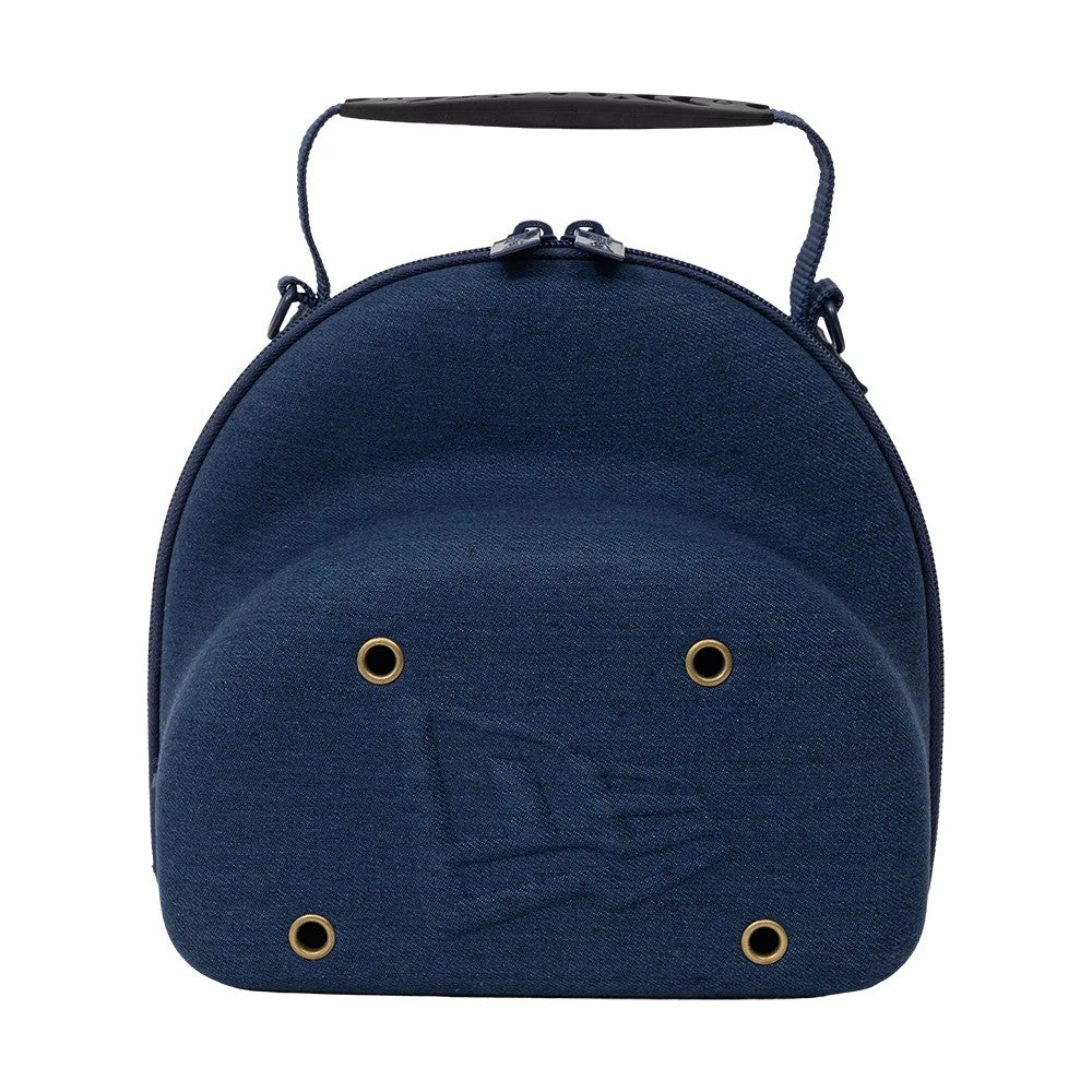 New Era Denim Navy 2Pk 59FIFTY Cap Carrier, front view showing the curved denim navy shell with a debossed New Era logo, gold eyelets evenly spaced on the surface, and a carry handle attached to the top of the case.